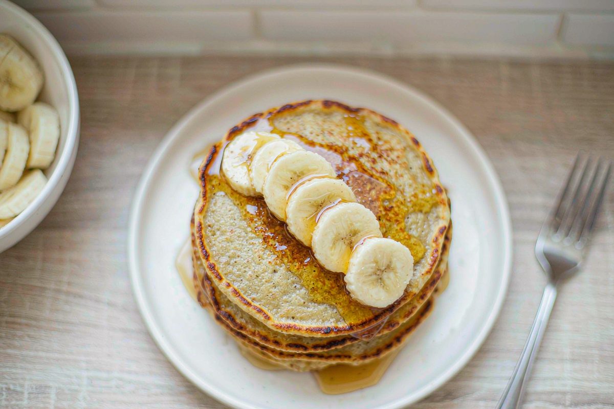 Stack of banana oat pancakes with sliced banana and maple syrup